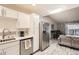 Open-concept kitchen with stainless steel appliances, white cabinets, and breakfast bar overlooking the living area at 3144 S Wheeling Way # 401, Aurora, CO 80014