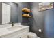 Stylish powder room with floating shelves, modern fixtures, and dark blue walls at 3550 Uinta St # 6, Denver, CO 80238