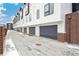 Row of modern townhome garages with gray doors and snow-covered driveway in a residential area at 3550 Uinta St # 6, Denver, CO 80238