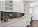 Chic butler's pantry with granite counters, a dark backsplash, and glass-front cabinetry for elegant display at 8075 S Vandriver Way, Aurora, CO 80016