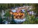 Aerial view of the property, showcasing the home's architecture, surrounding forest, and winter landscape at 30 W Ranch Trl, Morrison, CO 80465