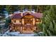 Rear exterior view of home with stone accents and decks visible between trees and winter landscaping at 30 W Ranch Trl, Morrison, CO 80465