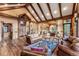 Open-concept living room featuring a stone fireplace, wood floors, exposed beams, and seamless flow to the dining area at 30 W Ranch Trl, Morrison, CO 80465