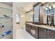 Well-appointed bathroom with granite counters, dark cabinets, glass display shelves and dual sinks at 2971 Fall River Rd, Idaho Springs, CO 80452