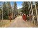 View of a home across a stream showing the driveway and gate on a wooded lot at 2971 Fall River Rd, Idaho Springs, CO 80452