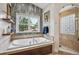 Bright bathroom features a soaking tub with marble surround and separate shower with glass block window at 583 S York St, Denver, CO 80209