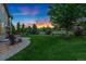 Spacious backyard with lush green lawn, a stone pathway, mature trees and manicured landscaping at 2647 Gray Wolf Loop, Broomfield, CO 80023