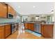 Open kitchen with stainless steel appliances, wood cabinetry, and seamless flow to the living area at 2647 Gray Wolf Loop, Broomfield, CO 80023
