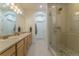 Bright bathroom featuring double sinks, wood cabinets, and glass enclosed shower at 11277 Osage Cir # E, Westminster, CO 80234