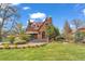 Charming brick Tudor home with lush landscaping, stone walkway, and covered porch entrance at 6285 W 35Th Ave, Wheat Ridge, CO 80033
