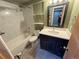 Bathroom with a white marble tiled shower/bathtub, dark blue vanity, and modern fixtures at 9852 W 76Th Ave, Arvada, CO 80005