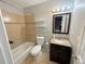 Full bathroom with a tub, toilet, and vanity with granite countertop, plus decorative tile accents at 9852 W 76Th Ave, Arvada, CO 80005