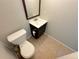 Cozy half bathroom featuring a dark vanity with a white sink and a nearby toilet, all above a tile floor at 9852 W 76Th Ave, Arvada, CO 80005