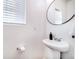 A powder room with a pedestal sink, round mirror, and neutral décor at 10669 Worchester Dr, Commerce City, CO 80022