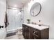 Modern bathroom featuring a stand-up shower, dark vanity, and stylish round mirror at 10669 Worchester Dr, Commerce City, CO 80022