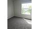 This is a bedroom with light walls, gray carpet, and a window that brings in natural light at 5151 Jasper St, Denver, CO 80239