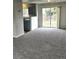 Open-concept living area with neutral carpet, sliding glass doors and view into the kitchen at 5151 Jasper St, Denver, CO 80239