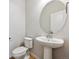 Clean half bathroom with toilet, pedestal sink, round mirror, and ample space at 1400 Colony Dr, Erie, CO 80026