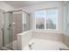 Bathroom featuring a glass-enclosed shower, soaking tub, and neutral tile surround at 5479 Lost Meadow Trl, Castle Rock, CO 80104