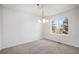 An empty dining room with neutral colored walls, carpet, chandelier, and view from a large window at 5479 Lost Meadow Trl, Castle Rock, CO 80104