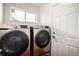 Laundry room with silver front load washer and dryer, white door and trim, and a window at 5479 Lost Meadow Trl, Castle Rock, CO 80104