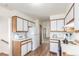 Bright kitchen with white cabinets, wood trim, and stainless-steel appliances leads to stairway and entry at 19855 Draco Dr, Monument, CO 80132