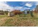 View of functional outbuildings, including a shed and gated enclosure, on a grassy lot under a blue sky at 19855 Draco Dr, Monument, CO 80132