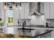 A bright kitchen showcases white cabinets, stainless appliances, a gas range, and a black countertop island with sink at 3059 Morningbird Ln, Castle Rock, CO 80109