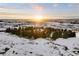 Breathtaking aerial view of the property surrounded by lush trees in a winter landscape during sunset at 7883 Fox Creek Trl, Franktown, CO 80116