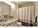 Bright bathroom with granite countertop, decorative mirror, and shower with striped curtain at 7472 S Memphis St, Aurora, CO 80016