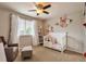 Adorable Bedroom featuring a white crib, comfortable chair, and decorative floral accents at 7472 S Memphis St, Aurora, CO 80016