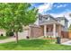 Beautifully landscaped front yard with a charming two-story home featuring a brick facade and a cozy front porch at 7472 S Memphis St, Aurora, CO 80016