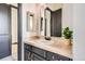 Bathroom featuring stylish vanity, tan tile counters, gold mirror and fixtures at 7837 Inverness Blvd, Englewood, CO 80112