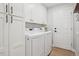 Well-equipped laundry room with modern washer and dryer, storage cabinets, and ample workspace at 9805 Keenan St, Highlands Ranch, CO 80130