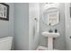 Stylish powder room with a pedestal sink, round mirror, and modern fixtures at 9805 Keenan St, Highlands Ranch, CO 80130