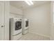 Clean laundry room with tile floor, white washer and dryer, and wire shelving at 10272 Greenfield Cir, Parker, CO 80134