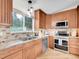 Well-lit kitchen with stainless appliances, wood cabinets, granite countertops, and a view to the backyard at 323 Paradise Rd, Golden, CO 80401