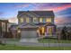 Charming two-story home features a brick and gray exterior with a two-car garage, lush lawn, and mountain views at 12917 Fox St, Westminster, CO 80234