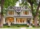 Charming two-story home with gray shingles, black fence, manicured landscaping, and welcoming front porch at 2130 S Milwaukee St, Denver, CO 80210