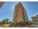 Exterior shot of a high-rise brick apartment building with balconies on a sunny day and landscaped ground level at 955 Eudora St # 407E, Denver, CO 80220
