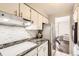 Galley kitchen with stainless steel appliances, granite countertops, and mosaic backsplash at 955 Eudora St # 407E, Denver, CO 80220