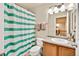 Clean bathroom with a green striped shower curtain, a wooden vanity, and a mirror at 1033 Petras St, Erie, CO 80516