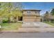 Charming two-story tan home featuring a three-car garage, stone accents, and a lawn at 1033 Petras St, Erie, CO 80516