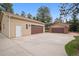Large detached garage with multiple bays, brown doors, and expansive driveway at 30321 Chestnut Dr, Evergreen, CO 80439