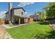Beautifully landscaped backyard featuring a lush lawn, covered patio, and privacy fence at 9494 Devonshire Pl, Highlands Ranch, CO 80126