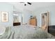 Bright bedroom with a comfortable bed, wood dresser with TV, light blue walls, and access to a bathroom at 9494 Devonshire Pl, Highlands Ranch, CO 80126