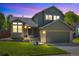Charming two-story home with a well-maintained lawn and attached two-car garage at twilight at 9494 Devonshire Pl, Highlands Ranch, CO 80126