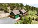 Aerial view of a green two-story home with a deck nestled among lush trees at 6066 Crawford Gulch Rd, Golden, CO 80403
