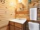 Bathroom with wood walls, featuring a vanity and toilet, complemented by modern towel rack and mirror at 6066 Crawford Gulch Rd, Golden, CO 80403