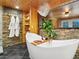 Charming bathroom with stone walls, wood accents, soaking tub and elegant chandelier at 6066 Crawford Gulch Rd, Golden, CO 80403